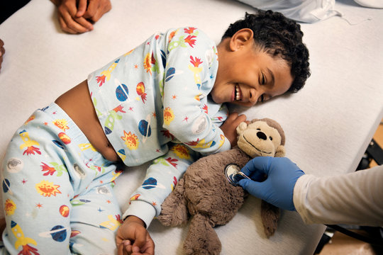 Boy laughing at doctor checking heartbeat of toy