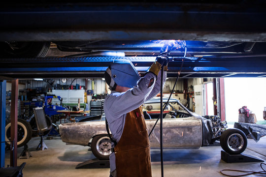 Mechanic welding chassis in workshop