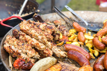 Kebabs of meat, sausages, potatoes in a rustic style fried in a large pan. Close up.