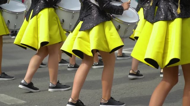 Street performance of festive march of drummers girls in yellow black costumes on city street