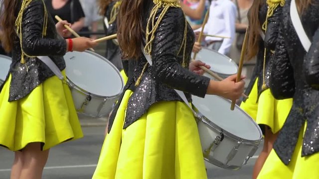 Street performance of festive march of drummers girls in yellow black costumes on city street