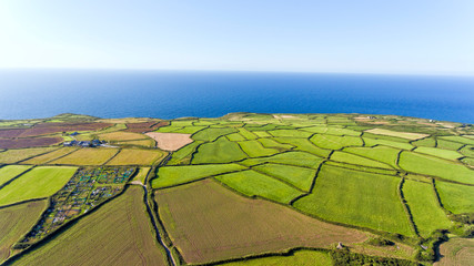 Aerial view of green, ploughed farm fields mosaic by Atlantic Ocean on the Cornish coast, on a...