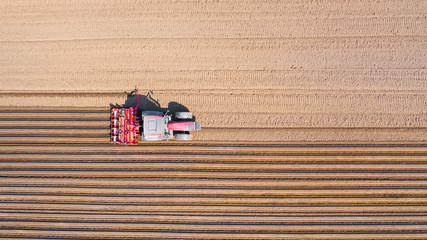 Tractor on a plowed field, top view. Agricultural field for planting vegetables. Tractor makes...