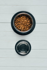 top view of bowl with pet food and empty bowl on wooden surface