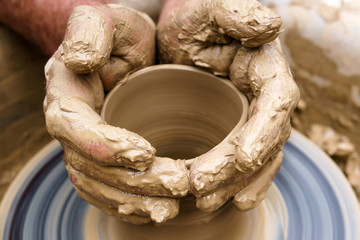 male hands making a mug on a potter's wheel
