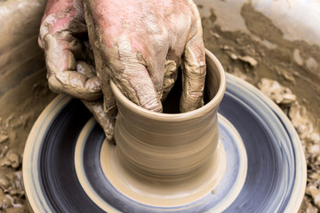 male hands making a mug on a potter's wheel