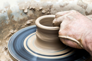 male hands making a mug on a potter's wheel