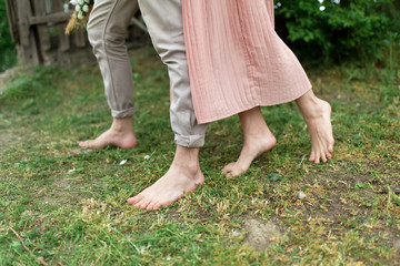 Young loving couple hugging and dancing on the green grass on the lawn. Beautiful and happy woman and man gently touch each other. Beautiful couple in love. girl in the dress and the guy in the shirt