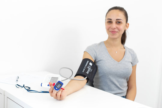 young smiling beautiful girl measures the pulse and blood pressure at the reception of a therapist