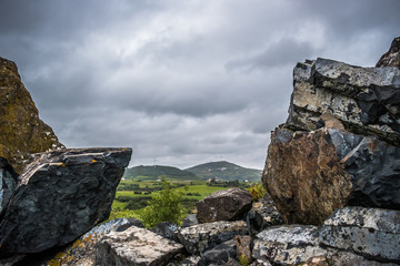 Green landscape with mountains and wind towers in background framed by rocks