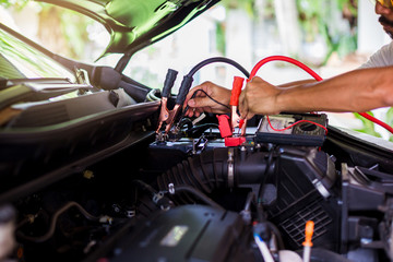 Auto mechanic use voltmeter to check voltage level in car battery. Auto mechanic working in garage....