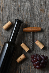 Wine Bottle on a rustic old wood table with grapes, corkscrew and corks