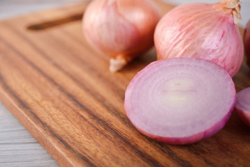whole and half cut shallotg on wooden cutting board