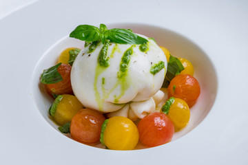 Salad with buratta cheese on white plate