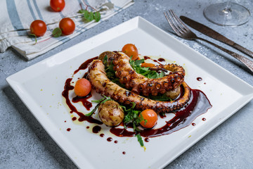 grilled octopus with vegetables on a white plate