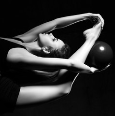 Young sporty woman doing gymnastics stretching fitness exercises workout with ball in sport club