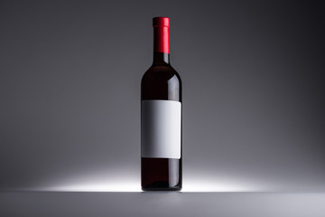 bottle of red wine and blank label on dark background with back light