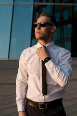 Businessman on the street in sunglasses watching the sunset. Man in a business suit and sunglasses watching the sunset