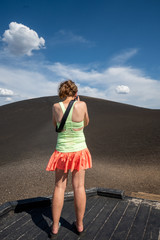 Woman photographer wearing bright clothes photographs the Inferno Cone in Craters of the Moon National Monument