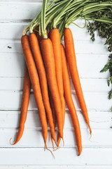 Gorgeous bunch of picked carrots with the leaves still on the stalks laying on an antique box.