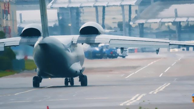 War plane (Combat plane) is taxiing on the taxiway after landing in rainy weather. Back view