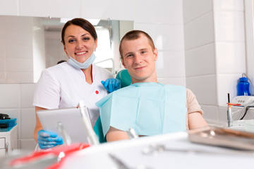 Portrait of a dentist discussing a treatment plan with a patient on a tablet