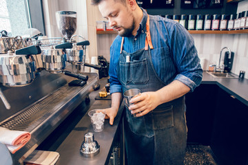 Caucasian handsome bearded man barista making cold iced coffee cappuccino latte in shaker. Waiter server pouring drink in plastic transparent cup. Small business and person at work concept.