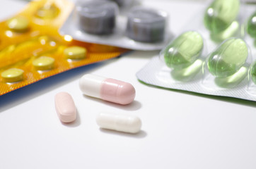 packings of pills and capsules of medicines in different position on white background