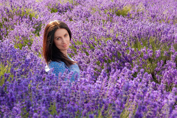French looking mature caucasian woman with blue eyes and brown hair, forward facing the camera with a calm look on her face is surrounded by a purple lavender field with copy space