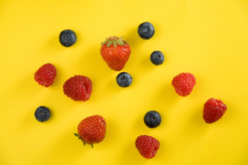 Fototapeta na wymiar Fresh Blueberries, Strawberries and Raspberries on Yellow Background