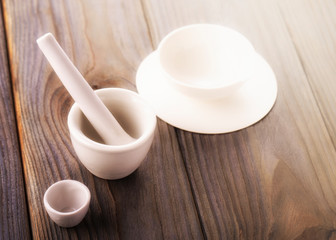 Small ceramic mortar,  bowl  and pestle on wooden background