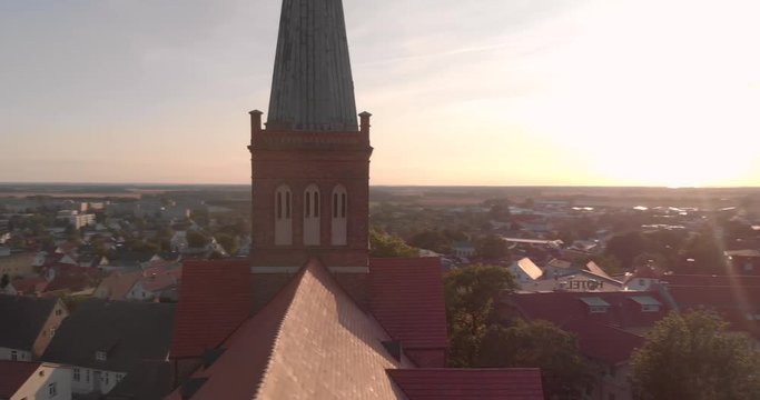A Point of interrest aerial drone shot of a red brick church of in a little town in northern Germany, while flying in golden hour, vertigo effect