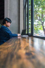 Fototapeta premium Asian student using laptop at rustic garden view coffee