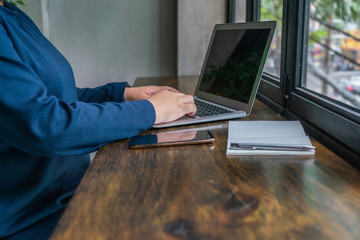 Close up photo of woman hand typing laptop at rustic table 