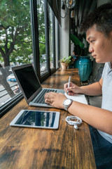 Fototapeta na wymiar Asian businessman working on laptop at beautiful rustic coffeeshop
