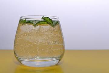 Refreshing drink with gas bubbles. Nalit in a transparent glass. It laid crushed ice. Decorated with mint leaves.