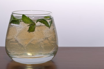 Refreshing drink with gas bubbles. Nalit in a transparent glass. It laid crushed ice. Decorated with mint leaves.