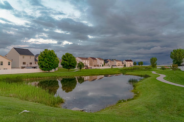 Fototapeta na wymiar Scenic neighborhood park with a shiny pond and pathway under an overcast sky