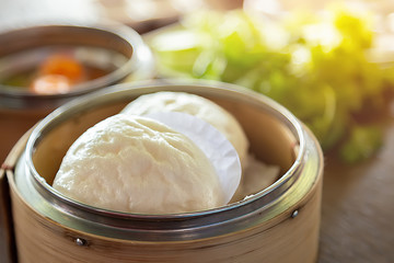 Steamed buns in a cup made of bamboo and vegetables on the table.Steamed food is a popular food in East Asia.