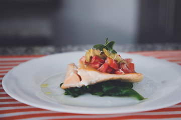 Baked salmon grilled pepper lemon and salt on a white plate with lettuce leaves