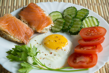 Fried eggs with spices, salmon, tomatoes, cucumbers, parsley