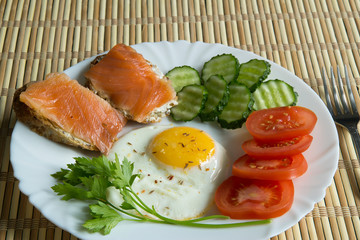 Fried eggs with spices, salmon, tomatoes, cucumbers, parsley