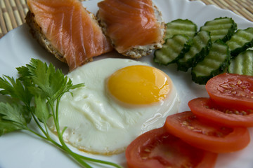 Fried eggs with spices, salmon, tomatoes, cucumbers, parsley