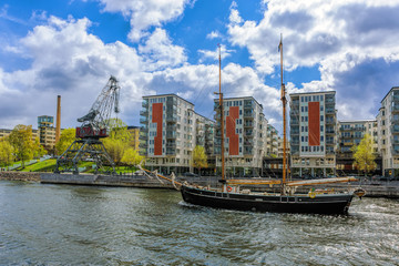 Twin-masted sailing ship passes underway of the canal Hammarby in Stockholm at sunny spring day.