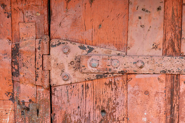 metal plank on an old wooden door. The metal level fastens wooden slats. Old wooden door with a metal bracket.