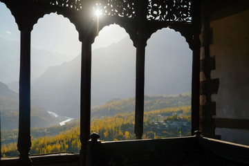Vintage window of Baltit fort with a blurry landscape view of Hunza Nagar valley and Karakoram mountain range in the background. Karimabad Gilgit Baltistan, Pakistan. Selective focus.