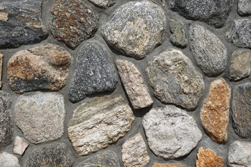 Rough stone wall with irregular rocks set in gray mortar