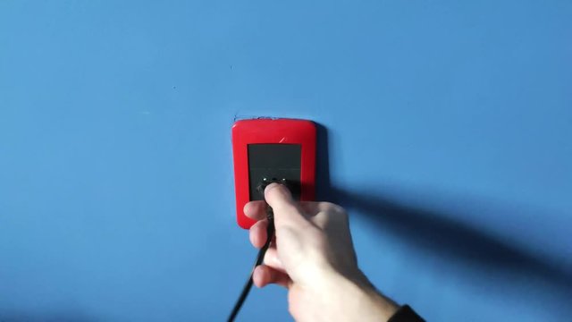 white man on blue wall unplugging a cable