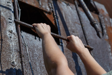 Fototapeta na wymiar Hands of a refugee girl on a steel ladder. Refugee concept. Attempt to escape.