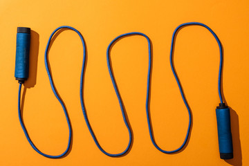 top view of blue and waved skipping rope on yellow